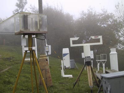 Pohled na „meteorologickou zahrádku“, kde je umístěna většina přístrojů jako např. PVM-100 pro měření obsahu kapalné vody v mlze (vpravo) nebo aktivní zařízení na odběr vzorků vody z mlh (vlevo).