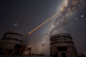 Dvě z pěti kopulí na observatoři Paranal v Chile a laser mířící do centra Galaxie. Foto: Yuri Beletsky/ESO.