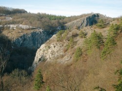 Kaňon Kačáku pod Sv. Janem – vlevo kolmá Dušičková stěna, dále vpravo vrchol Dlouhé skály s prudkými srázy ovlivněnými strmým sklonem vrstev. Nicméně i toto divoké údolí bylo od pravěku hojně navštěvováno, jak dokládají nálezy na úpatí Dušičkové stěny,  z jeskyně Na Průchodě a dalších míst (Sv. Jan, Květná). Foto V. Ložek jun.