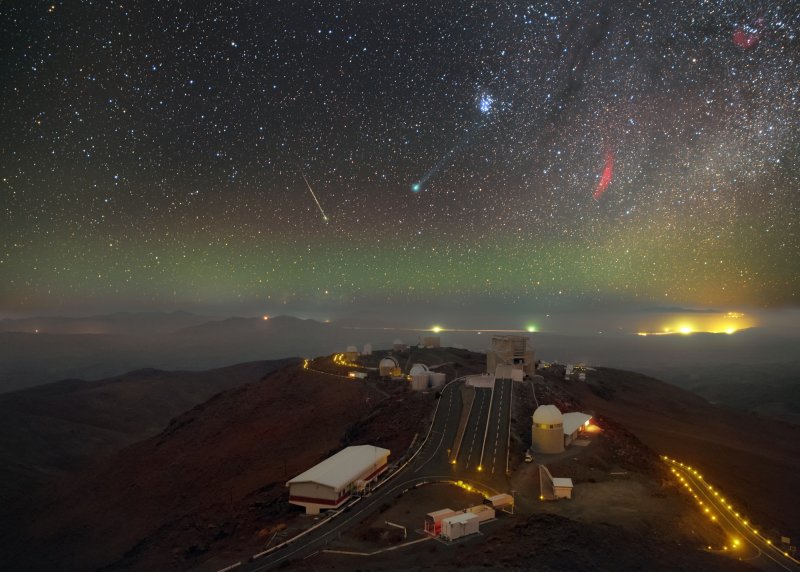 Příchod noci jako divadelní opona odhaluje dění, která se odehrává na bezoblačném nebi nad observatoří La Silla. Kometa Lovejoy září ve středu snímku zeleně, nad ní je hvězdokupa Plejády. Mlhovina Kalifornie (napravo od komety) ve formě červeného oblouku vytváří na snímku barevný kontrast. Na horizontu je vidět zelená vrstva atmosférického záření, tzv. airglow. Foto: ESO / P. Horálek.
