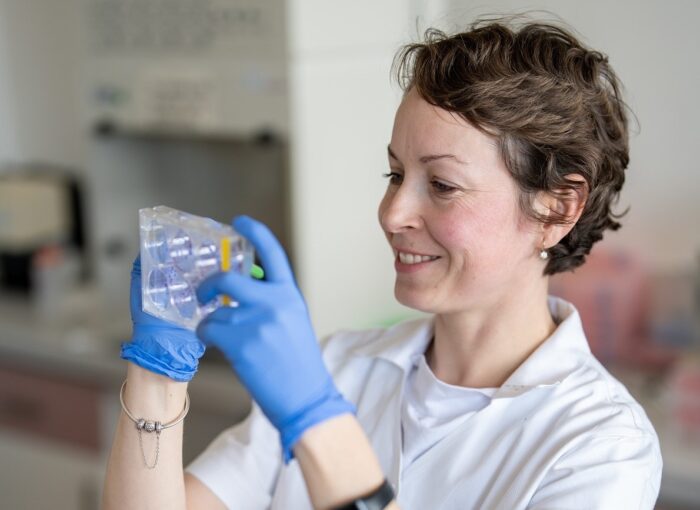 Scientist Veronika Vymetálková is looking at cells on a microtiter plate.